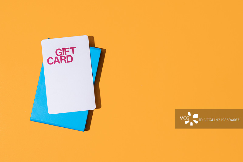 礼品卡放在蓝色盒子上，背景为橙色图片素材