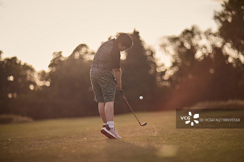 一位年轻的初级高尔夫球手在英国的风景优美的高尔夫球场上打球，正值夏末。图片素材