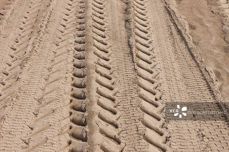 干燥棕色沙土上的沙轮胎印背景，车辆轮胎形状的轨迹线图片素材