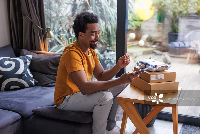 男人在家中用智能手机和信用卡愉快地进行网上购物图片素材