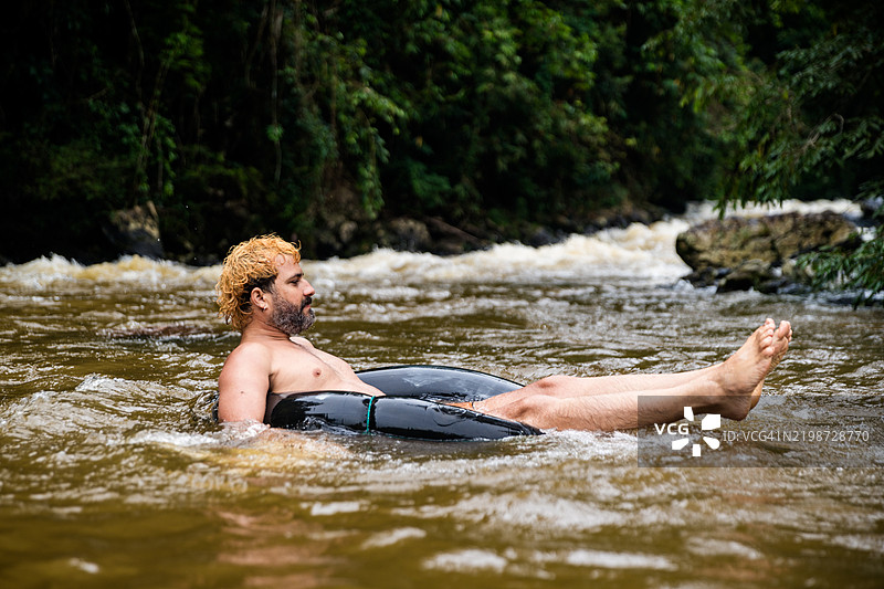 男子在河中享受充气圈的乐趣图片素材