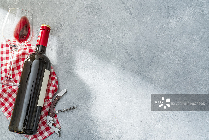 灰色背景上方的红酒瓶和酒杯。构图位于左侧，留有空白区域。图片素材