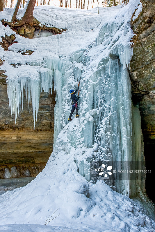 男子在密歇根州穆宁斯的冰冻瀑布上攀爬图片素材