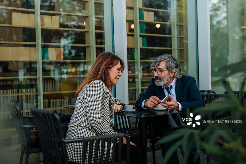 商业伙伴在咖啡馆开会，讨论工作并使用智能手机图片素材