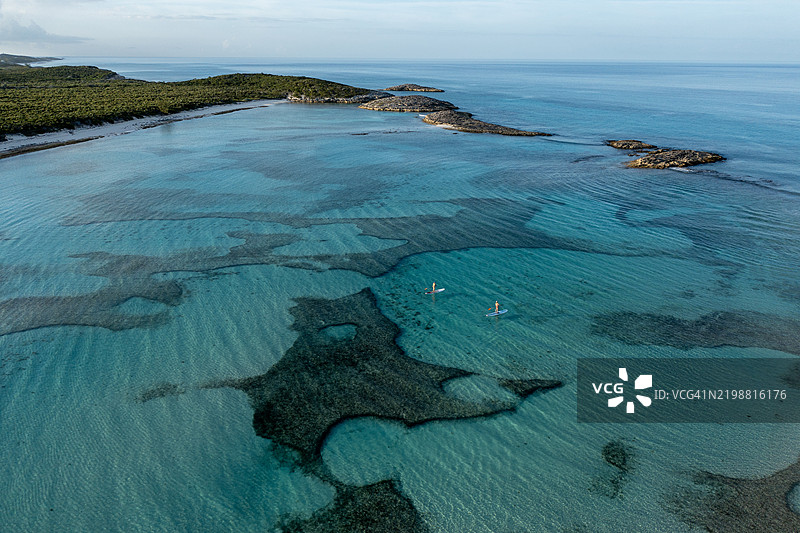 在巴哈马的埃克苏马群岛，两名女性在桨板上划水的空中视角图片素材