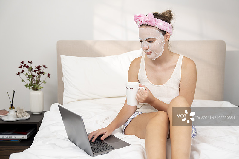 年轻女性在护肤过程中使用笔记本电脑图片素材