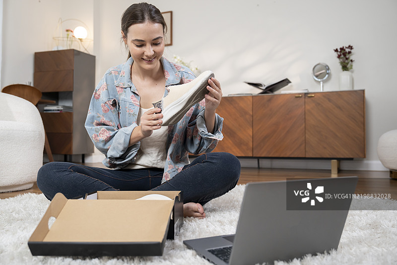 年轻女性在网上购物后收到了新靴子图片素材