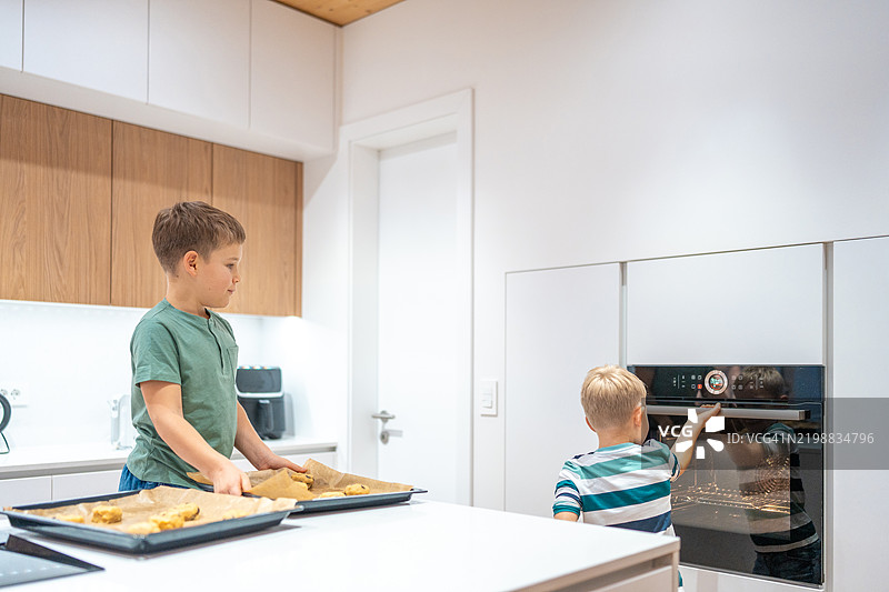 白人男孩在明亮的厨房里烘焙饼干图片素材