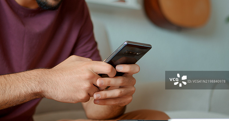 男性手部特写，使用手机发送短信或聊天。图片素材
