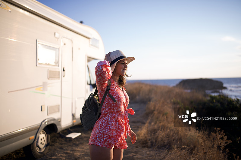 早晨的旅程：女人在日出时分走过她的房车。图片素材