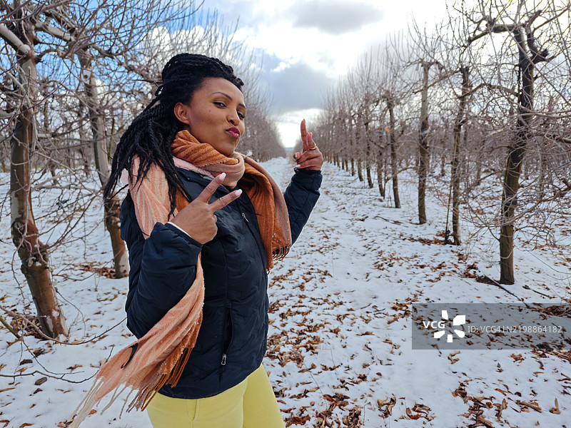 自信的女性在雪-covered果园中俏皮地摆姿势。图片素材