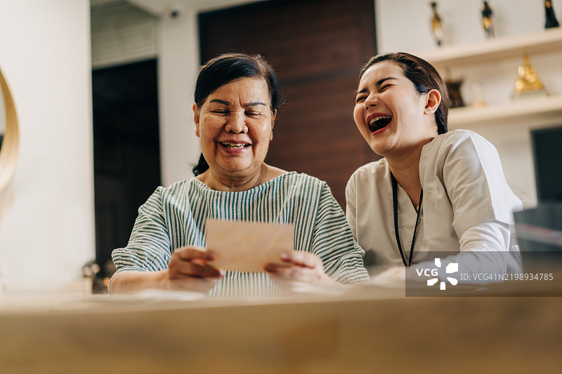 快乐的老人与护士分享怀旧的照片册时刻图片素材