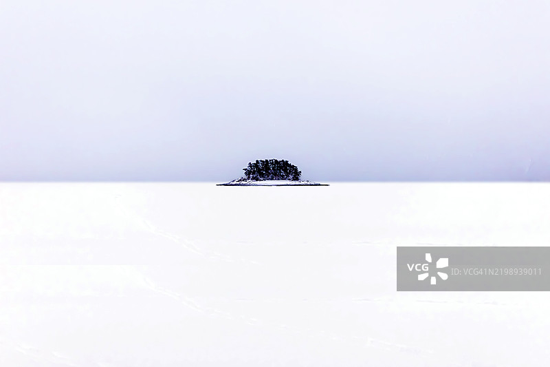 雪覆盖的广袤天地中的树木岛屿图片素材