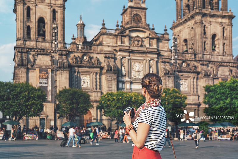 女人在日落时分用复古胶卷相机拍摄索卡洛主广场和墨西哥城大教堂。图片素材