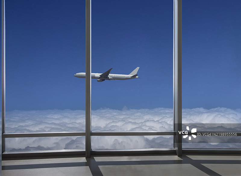 高楼办公室俯瞰云层上的飞行飞机。图片素材