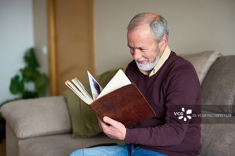 成年男子在家微笑着翻看旧相册图片素材