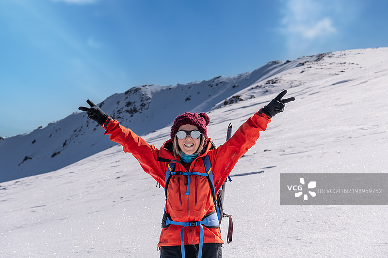 女登山者在高海拔山峰的顶峰做出和平手势。图片素材
