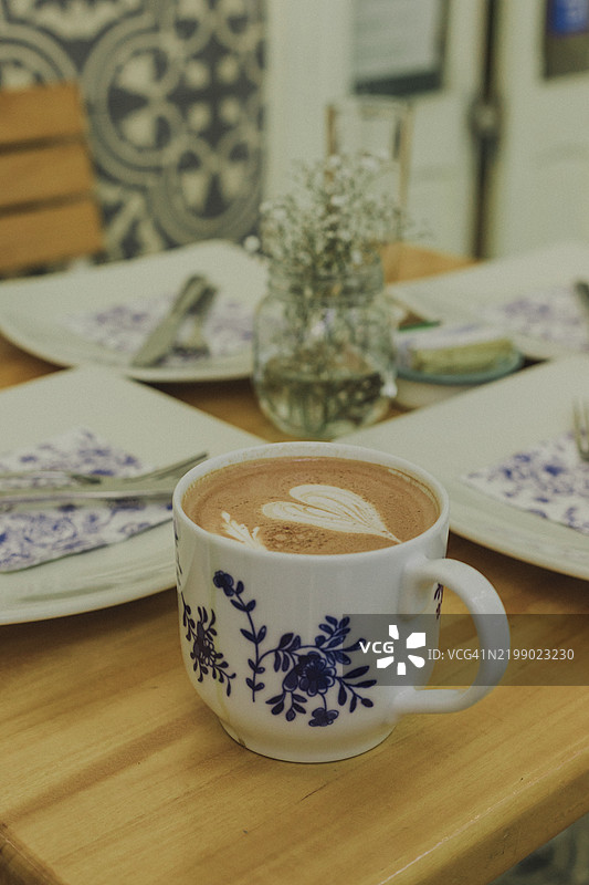 木桌上的精美咖啡杯中的心形拿铁艺术图片素材