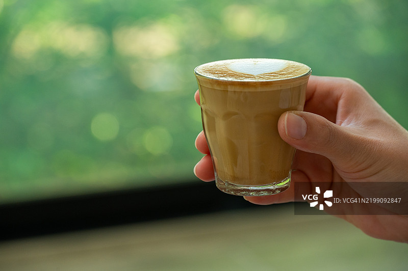女人手中拿着一杯小型拿铁的特写镜头。图片素材