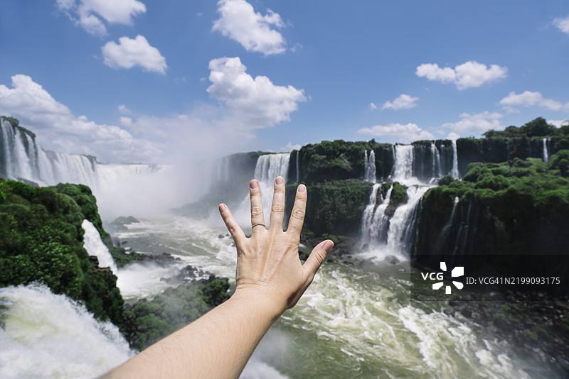 在巴西伊瓜苏瀑布前，无法辨认的女性张开手展示戒指图片素材
