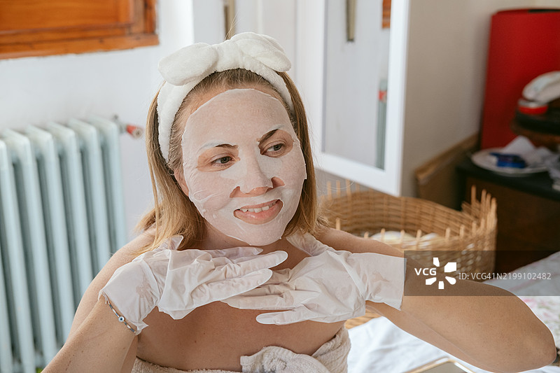 女性使用具有提拉效果的保湿面膜，面膜含有提拉和抗衰老活性成分。图片素材