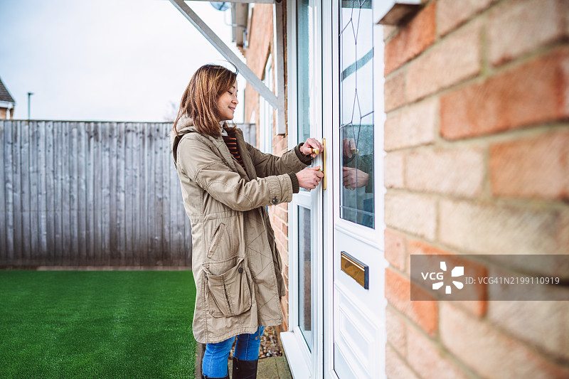 一位女性正在打开前门，回到家中。图片素材
