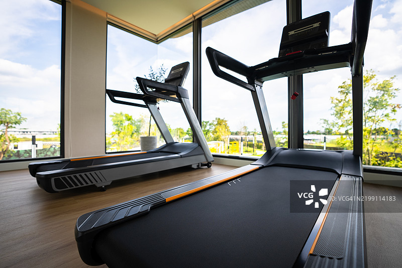 现代健身房，配有跑步机和大窗户图片素材