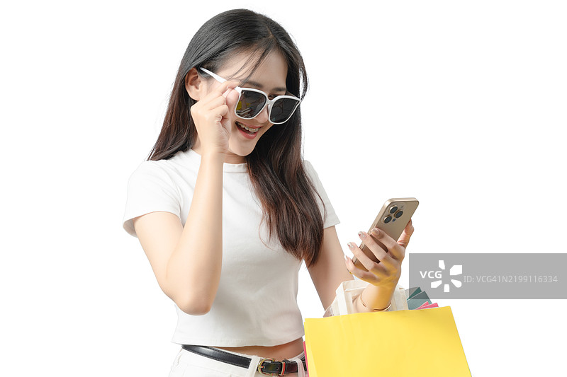 一位戴着太阳镜、穿着白衬衫的女性正在拿着手机。图片素材