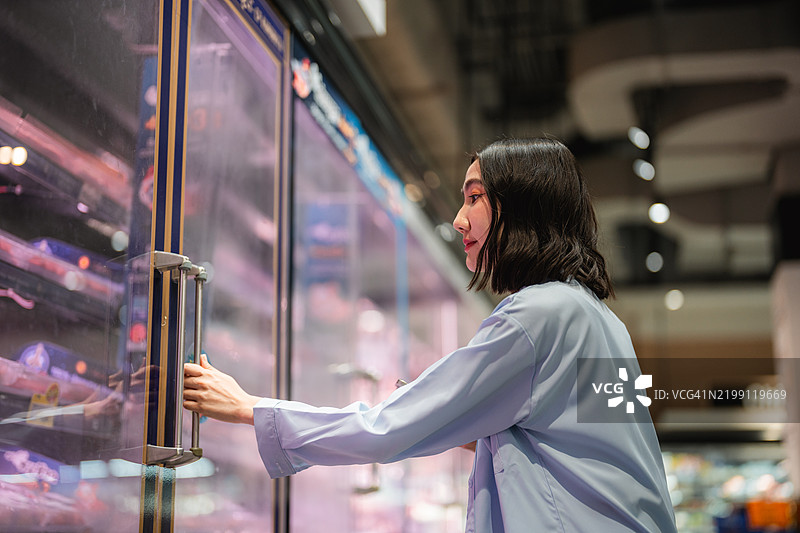 年轻的亚洲女性在超市中选择并挑选环保袋里的苹果或蔬菜图片素材