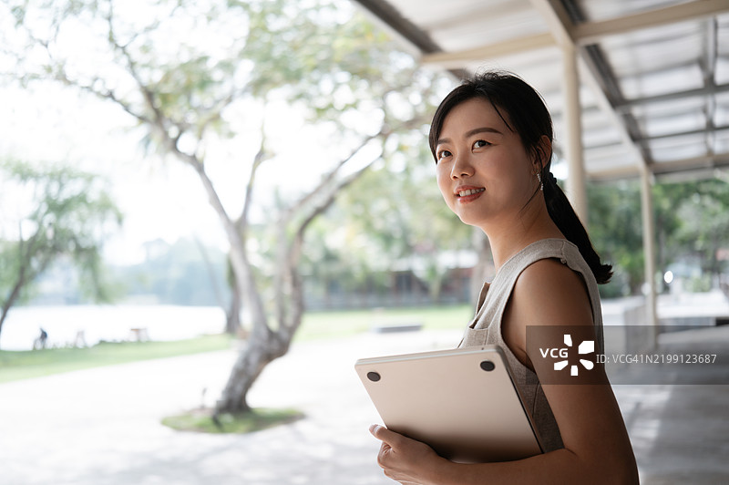 成功的亚洲女商人在户外手持笔记本电脑图片素材