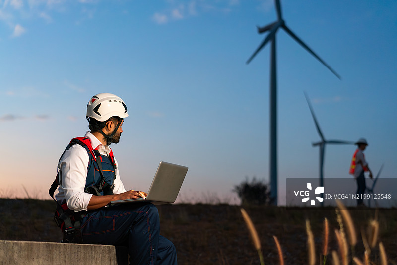 工程师在风电场的傍晚时分使用笔记本电脑工作图片素材