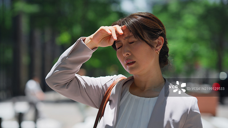 亚洲女商人在城市金融区的阳光明媚的极热天气中感到过热图片素材