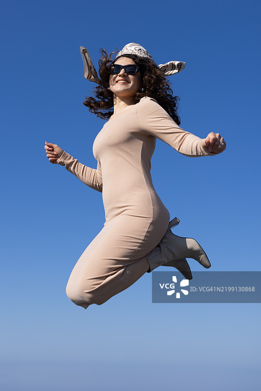 美丽的女人在天空中跳跃的低角度拍摄图片素材