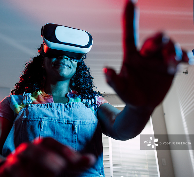在家中戴着虚拟现实头盔的女性玩耍图片素材