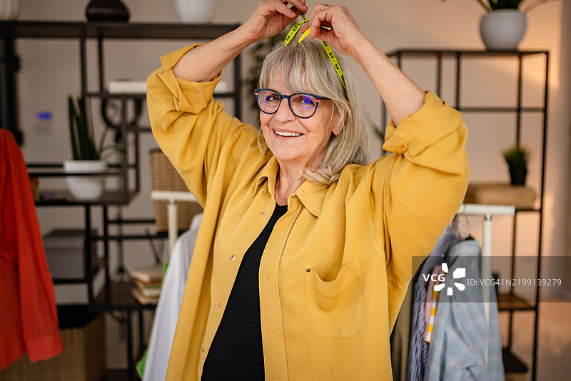 一位年长女性在创意工作室中缝制衣物，展示她的缝纫技巧和对设计的热情图片素材