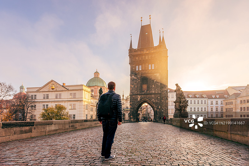 背包男士在捷克布拉格查尔斯桥上行走，背影。图片素材