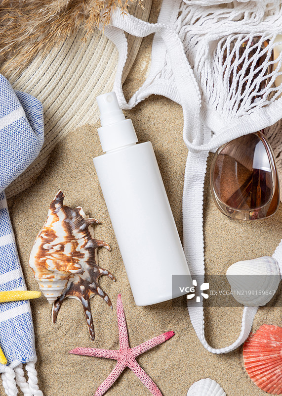 防晒喷雾瓶、太阳镜、毛巾、沙滩上的海星和贝壳、化妆品样品图片素材