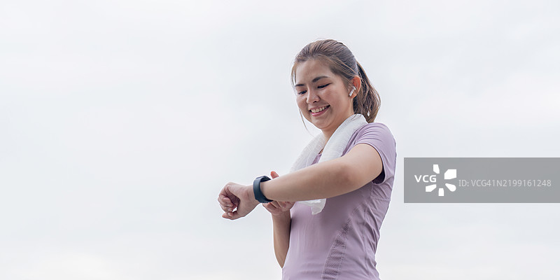 微笑的女性在锻炼后查看她的健身追踪器图片素材