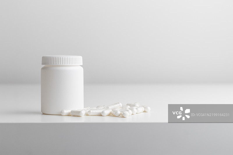 白色背景上的白色药丸和塑料药瓶，留有空白空间。医学和健康概念包括装有药丸或维生素的瓶子。高质量的照片展示横幅。图片素材