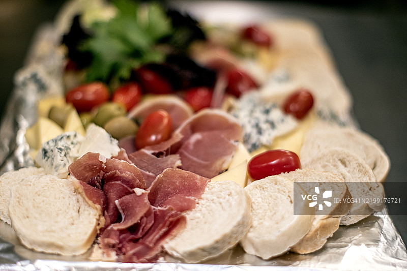 冷切肉、生火腿、橄榄、罗克福奶酪、樱桃番茄、生菜、帕尔马奶酪和面包板。拼盘。图片素材