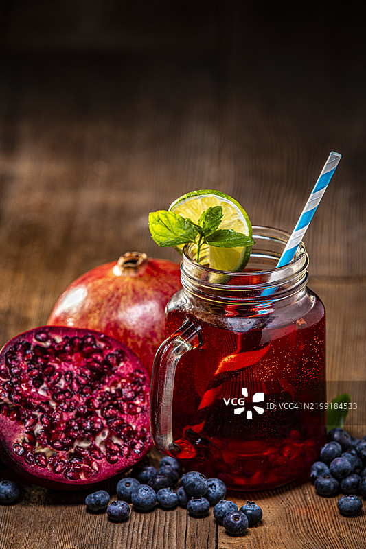 木质背景上的蓝莓和一片青柠的抗氧化石榴汁图片素材