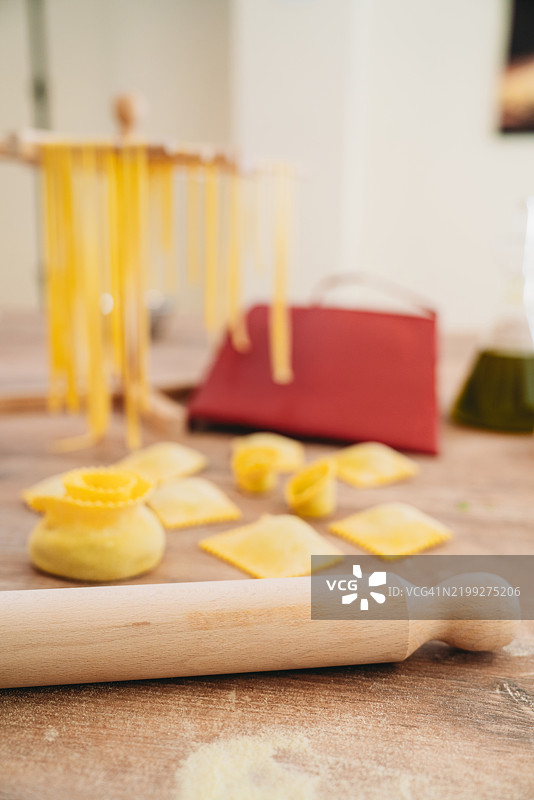 新鲜意大利面、饺子和意大利小饺子，配有木制桌上的擀面杖图片素材