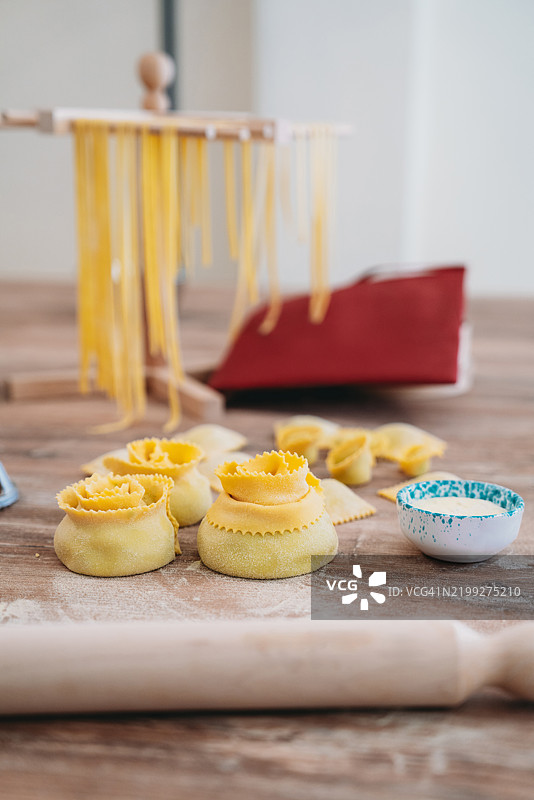 新鲜意大利面在木架上晾干，桌子上呈玫瑰形状。图片素材