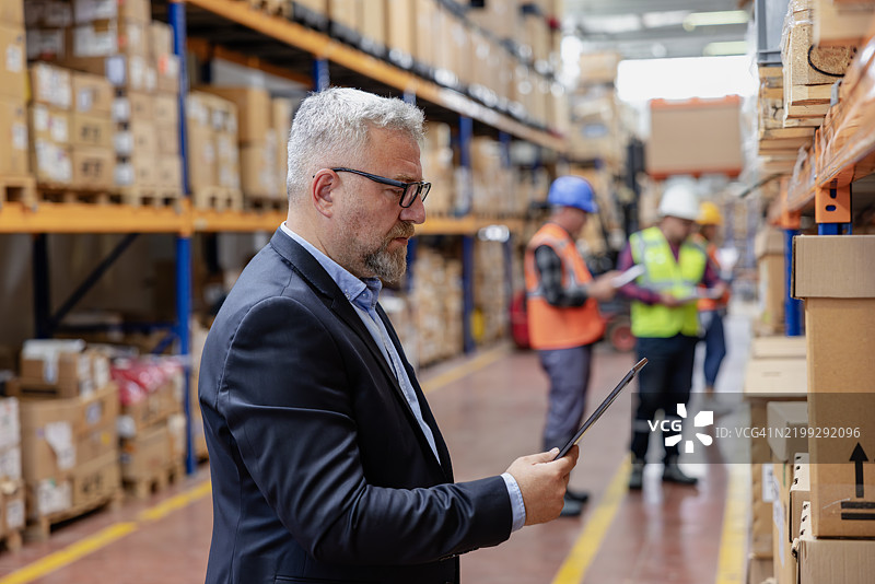 仓库中使用数字平板的工厂经理图片素材