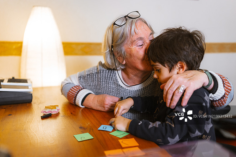祖母在家中与孙子玩字母时亲吻他图片素材