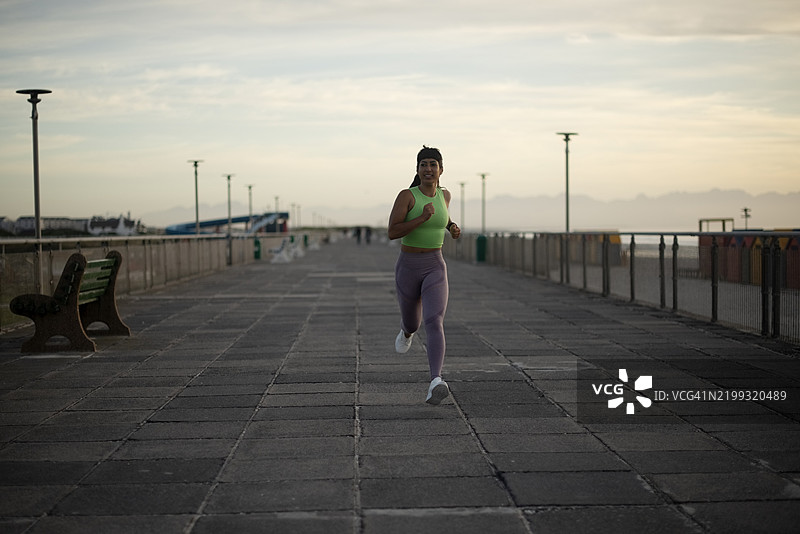 在海滩上晨跑的女性，进行马拉松训练、心肺锻炼和健康活动。运动挑战、能量和运动员在跑道上训练。图片素材