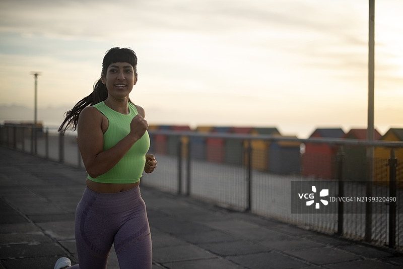 在海滩上跑步的女性，晨曦中进行马拉松训练、心肺锻炼和健康活动。锻炼挑战、能量和运动员在海滨长廊上训练的场景。图片素材