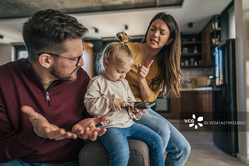 父母在家里争论女儿使用智能手机的事情图片素材