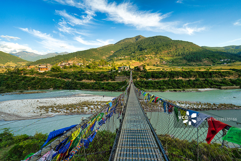 人们在布丹普纳卡的波楚河上，穿过装饰有祈祷旗的行人悬索桥。图片素材