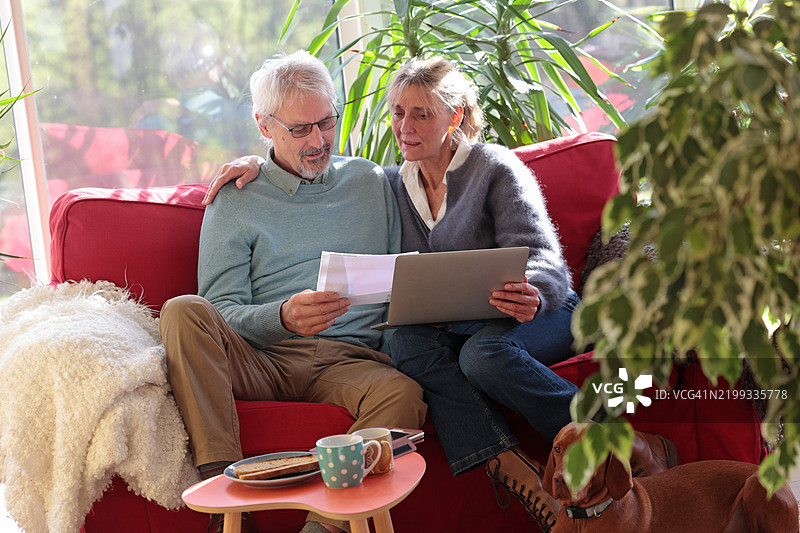 老年夫妇在家沙发上使用笔记本电脑图片素材